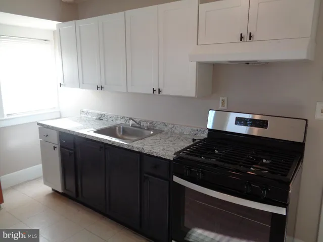 a kitchen with granite countertop white cabinets and black stove top oven