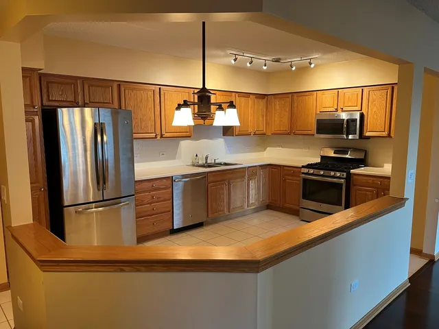 a kitchen with stainless steel appliances granite countertop a refrigerator a stove and a sink