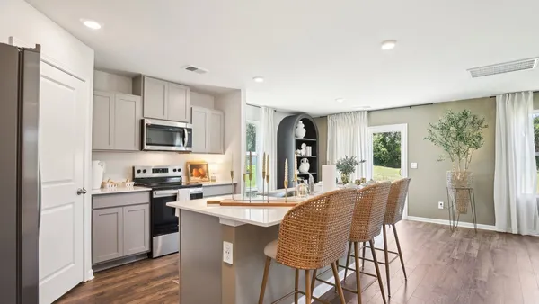 a kitchen with stainless steel appliances kitchen island granite countertop a stove a sink a refrigerator a dining table and chairs with wooden floor