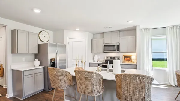 a view of kitchen with stainless steel appliances granite countertop dining table chairs and a refrigerator
