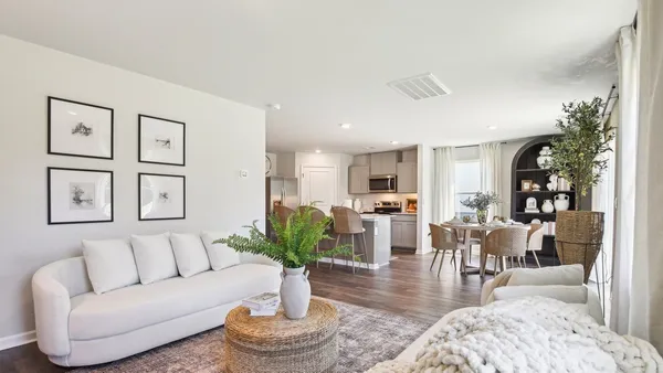 a living room with furniture potted plant and kitchen view