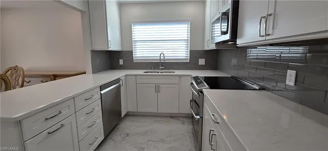 a kitchen with white cabinets and stainless steel appliances
