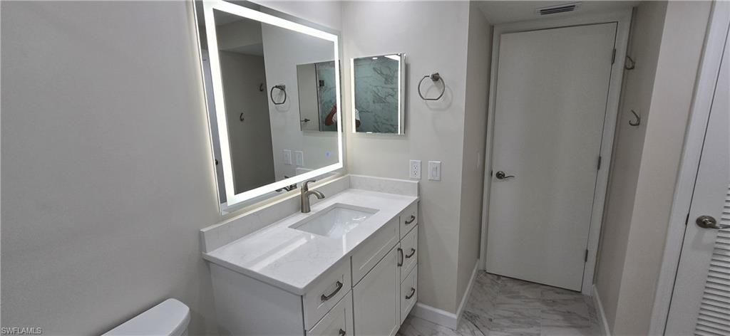 115 Georgetown Boulevard, Unit 115 Naples, FL 34112 - Photo 24 of 32 a bathroom with a sink vanity and a mirror