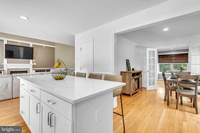 a kitchen with stainless steel appliances a stove top oven a sink dishwasher a refrigerator and white cabinets with wooden floor