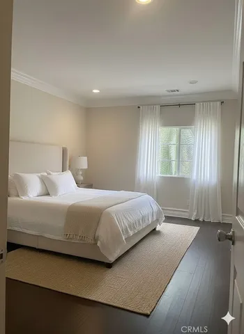 a bedroom with a bed lamp and a large window