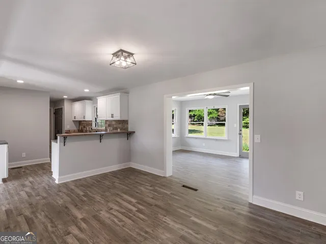 a view of an empty room with window and chandelier fan
