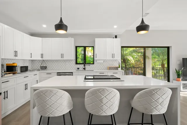 a kitchen with stainless steel appliances kitchen island a large window in it and white cabinets