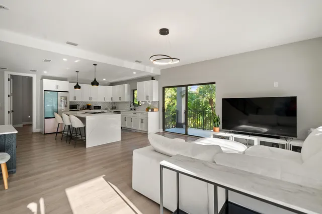 a kitchen with stainless steel appliances kitchen island granite countertop a sink and a stove top oven with wooden floor