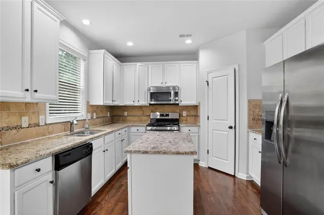 a kitchen with stainless steel appliances granite countertop a refrigerator a sink a stove a microwave and wooden cabinets