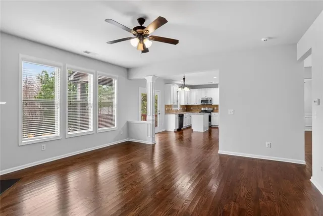 a view of an empty room with wooden floor and a window