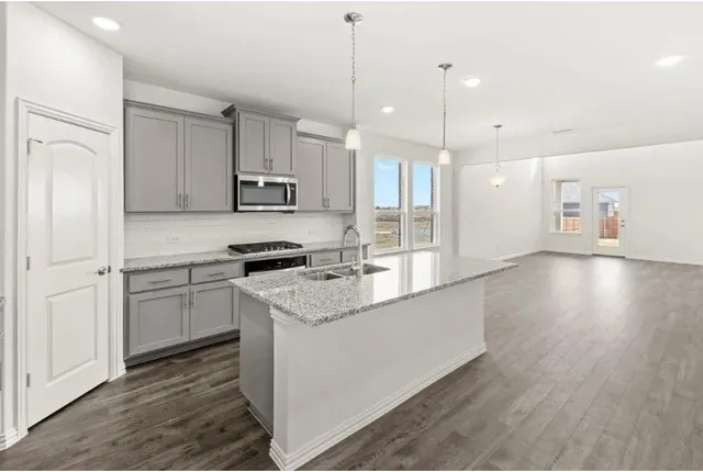 a kitchen with granite countertop a sink stove and refrigerator
