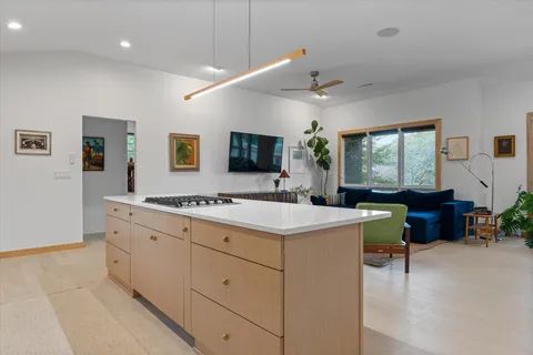 a large white room with kitchen island stainless steel appliances sink and cabinets