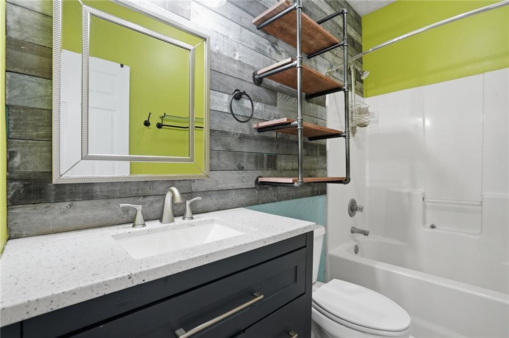 3664 McEver Lake Road Pendergrass, GA 30567 - Photo 18 of 39 a bathroom with a granite countertop sink a toilet and bathtub