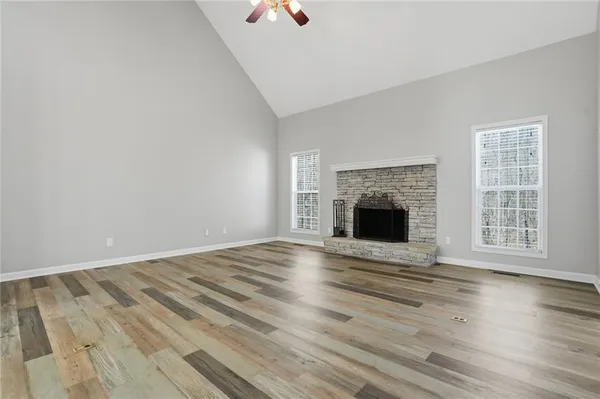 an empty room with wooden floor fireplace and window