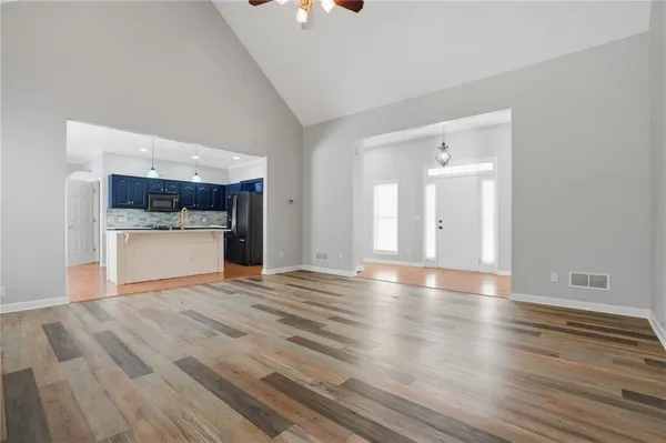 an empty room with wooden floor and a kitchen