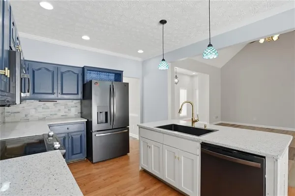 a kitchen with granite countertop a refrigerator a stove a sink and a counter space