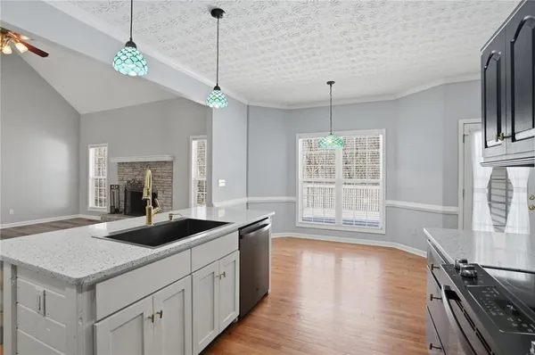 a kitchen with stainless steel appliances granite countertop a sink a stove and a wooden floor