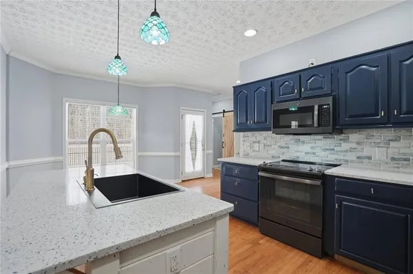 a kitchen with kitchen island granite countertop a stove a sink and a microwave