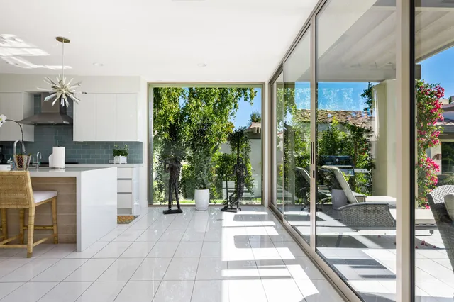 a living room with furniture a flat screen tv and a floor to ceiling window