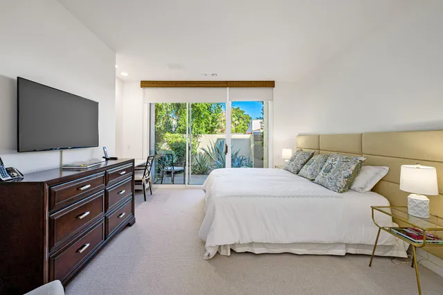 a bedroom with a bed and a flat tv screen on dresser