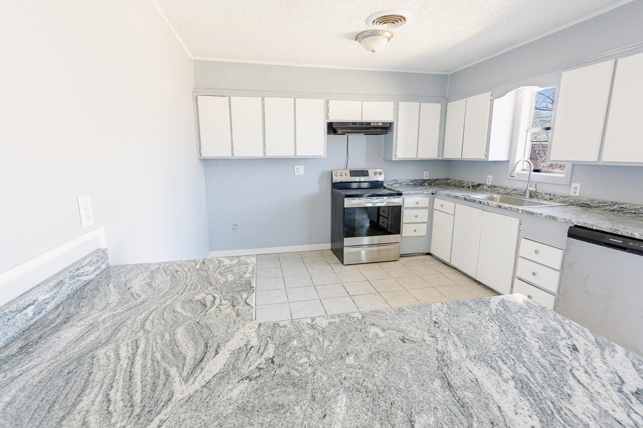 2802 40th Street Lubbock, TX 79413 - Photo 19 of 21 a kitchen with granite countertop a stove top oven sink and cabinets