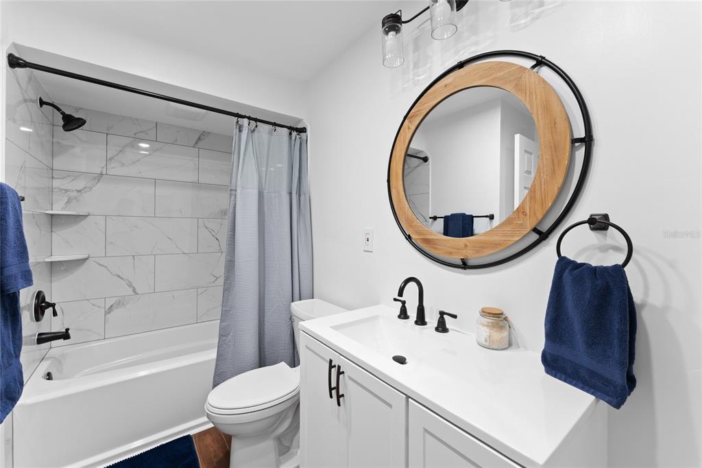 909 Bentwood Lane, Unit 1 Port Orange, FL 32127 - Photo 14 of 36 a bathroom with a sink a mirror a toilet and a tub