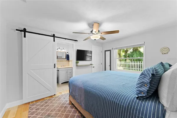a bedroom with a large bed a flat tv screen and a window