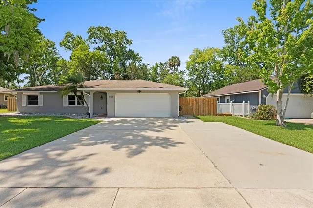 a front view of a house with a garden and trees