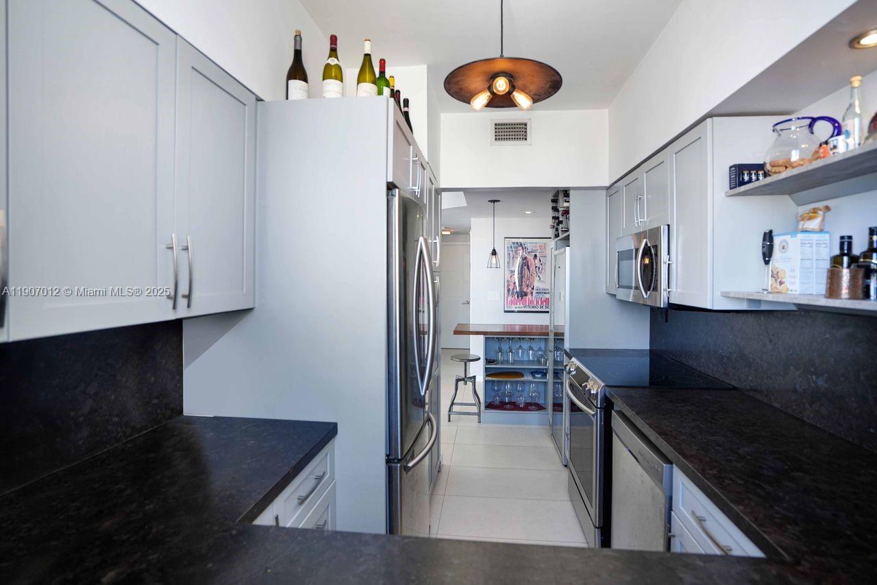 1621 Bay Road, Unit PH1 Miami Beach, FL 33139 - Photo 12 of 32 a kitchen with stainless steel appliances granite countertop a stove and cabinets
