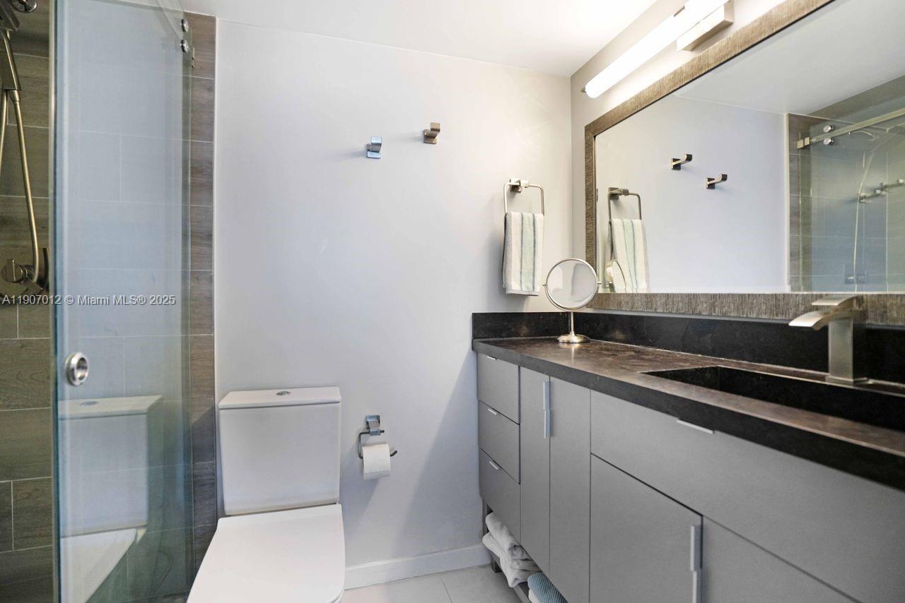 1621 Bay Road, Unit PH1 Miami Beach, FL 33139 - Photo 16 of 32 a bathroom with a granite countertop sink a toilet and a mirror