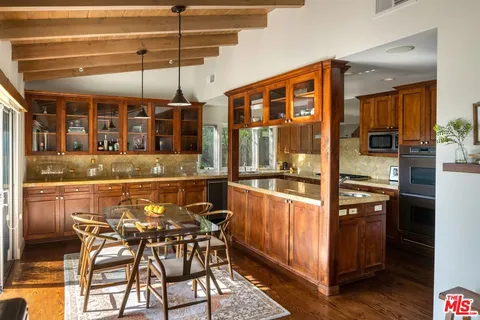a dining room with stainless steel appliances kitchen island granite countertop a table chairs and a wooden floor