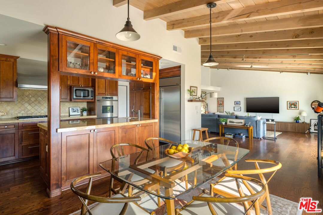 3823 Cody Road Sherman Oaks, CA 91403 - Photo 18 of 38 a dining room with stainless steel appliances kitchen island granite countertop a table chairs and a wooden floor