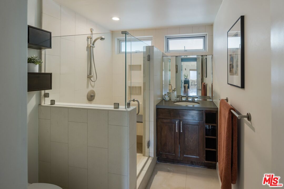 3823 Cody Road Sherman Oaks, CA 91403 - Photo 25 of 38 a bathroom with a shower sink and mirror