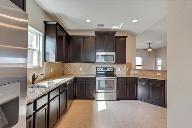 a kitchen with stainless steel appliances granite countertop a sink stove microwave and cabinets