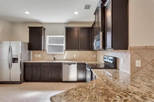 a kitchen with stainless steel appliances granite countertop a sink and a refrigerator
