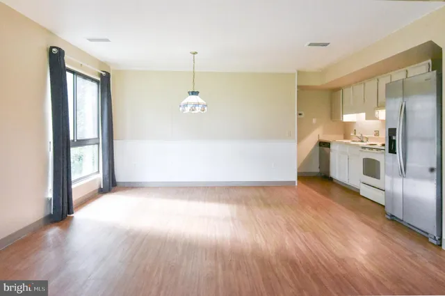 a view of a kitchen with wooden floor electronic appliances and a window