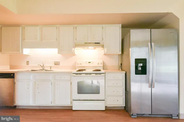a view of an empty room with wooden floor fireplace and a window