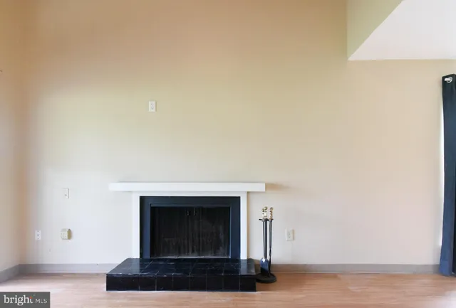 a view of an empty room with wooden floor and a fireplace