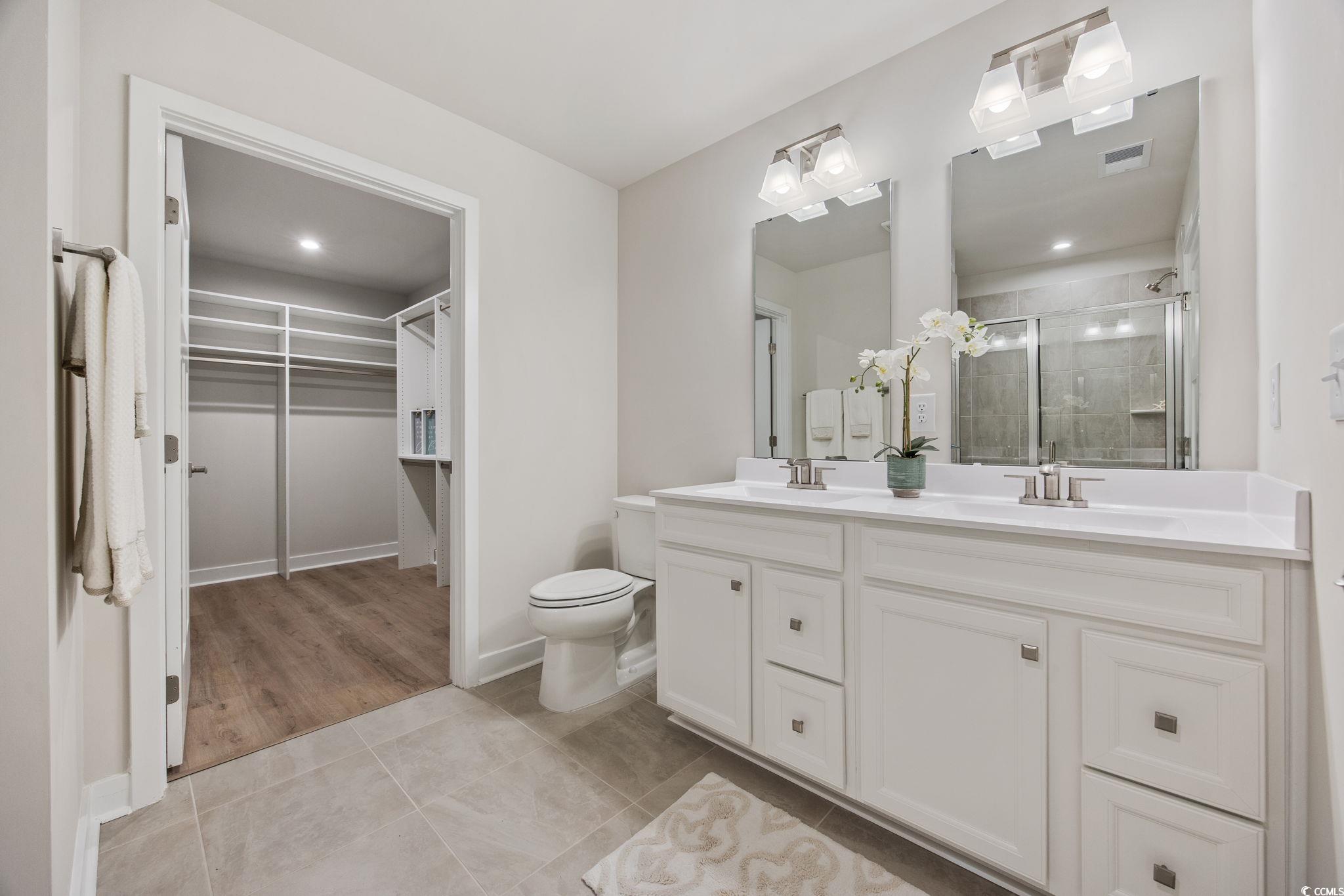 345 Bent Green, Unit 90A Murrells Inlet, SC 29576 - Photo 18 of 39 Bathroom with a walk in closet, double vanity, light tile patterned floors, and a stall shower