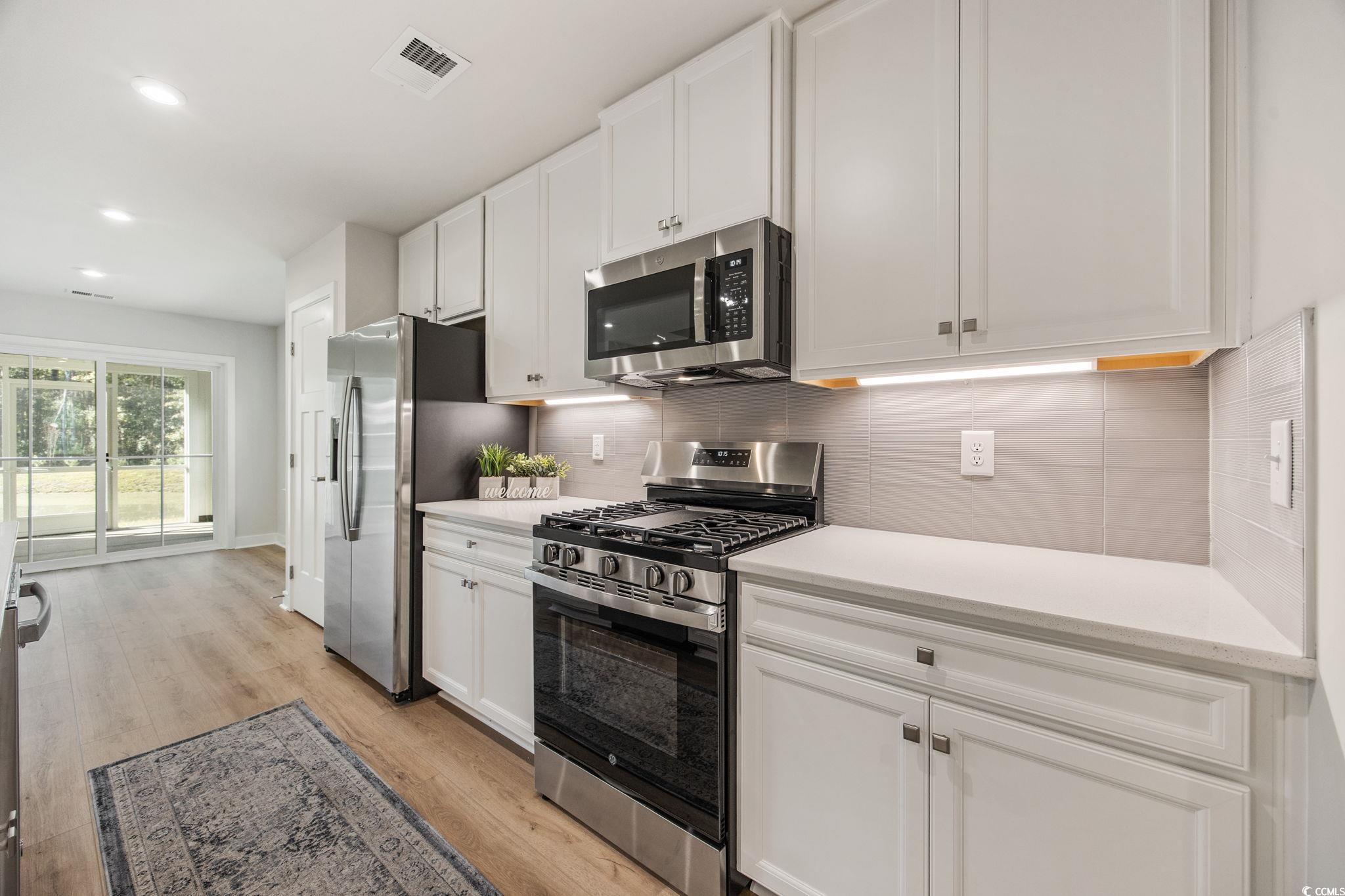 345 Bent Green, Unit 90A Murrells Inlet, SC 29576 - Photo 9 of 39 Kitchen with appliances with stainless steel finishes, white cabinets, tasteful backsplash, light wood finished floors, and recessed lighting