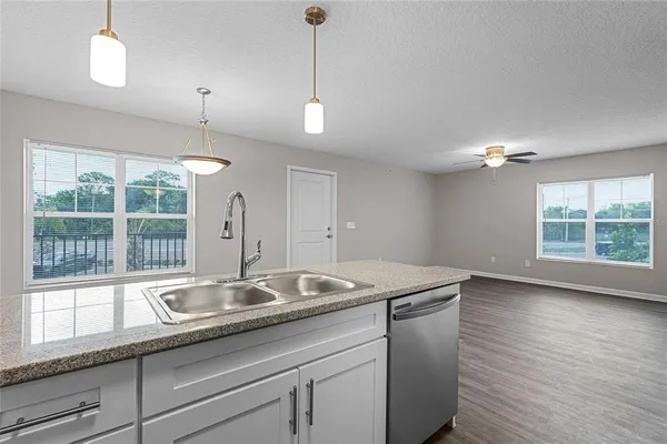 a kitchen with stainless steel appliances granite countertop a sink a window and chairs