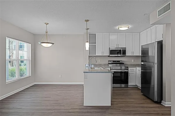 a kitchen with stainless steel appliances a refrigerator a stove a sink cabinets and wooden floor