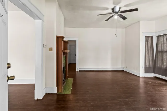a view of an empty room with wooden floor and a ceiling fan