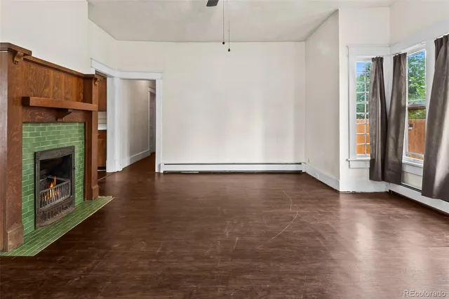 an empty room with wooden floor fireplace and windows
