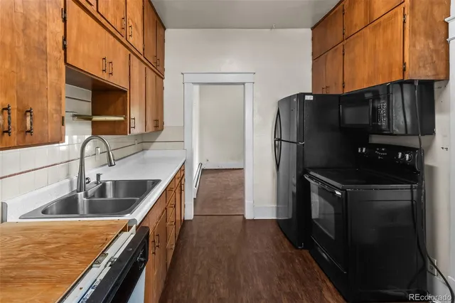 a kitchen with granite countertop a refrigerator a stove and wooden cabinets