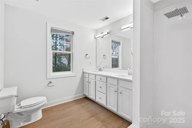 a bathroom with a double vanity sink a toilet and a window