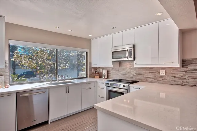 a kitchen with stainless steel appliances granite countertop a stove top oven a sink a microwave and cabinets