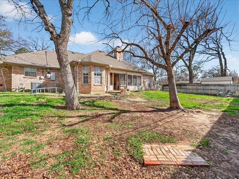 1704 South Bowen Road Pantego, TX 76013 - Photo 35 of 37 Expansive backyard featuring mature trees, a privacy fence, a brick veneer exterior, and a covered patio area