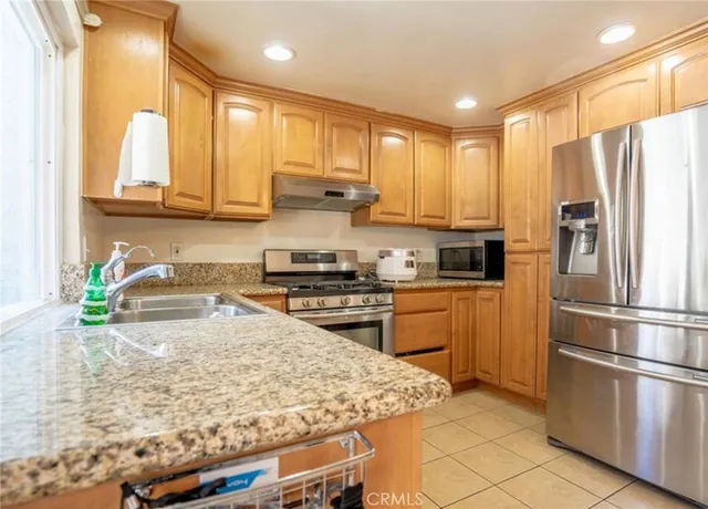 a kitchen with stainless steel appliances granite countertop a refrigerator sink stove microwave and cabinets