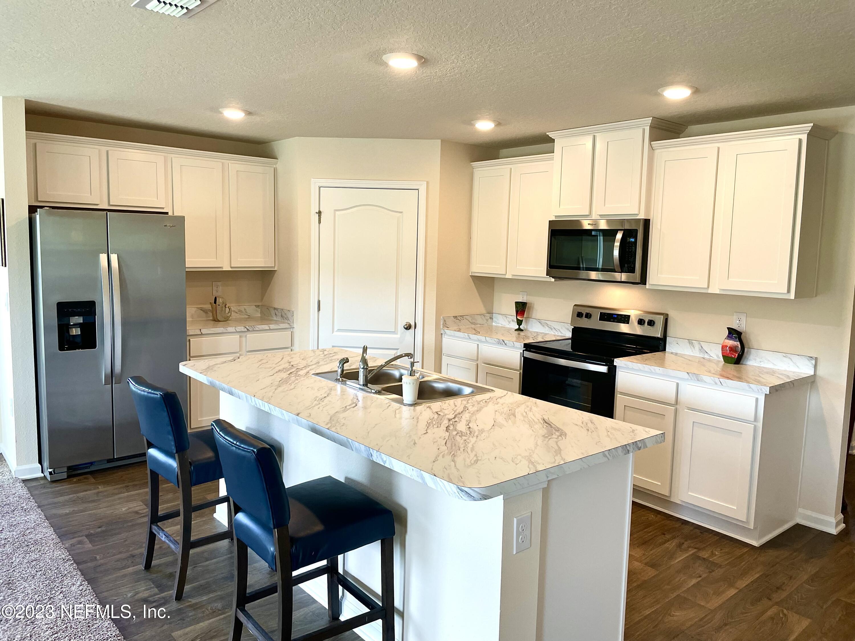 115 Falcon Ridge Road St. Augustine, FL 32084 - Photo 7 of 27 a kitchen with stainless steel appliances a stove a sink a microwave a refrigerator and white cabinets
